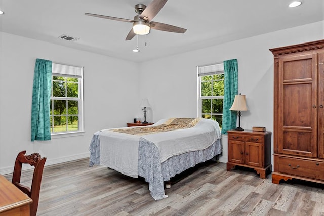 bedroom with multiple windows, ceiling fan, and light hardwood / wood-style flooring