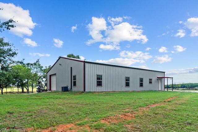 view of outbuilding featuring a garage, a lawn, and central air condition unit