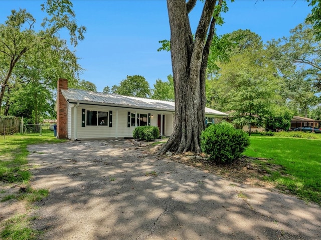 1313 Glass Ave, Diboll, TX 75941 - ranch-style home featuring asphalt driveway, a chimney, and a metal roof