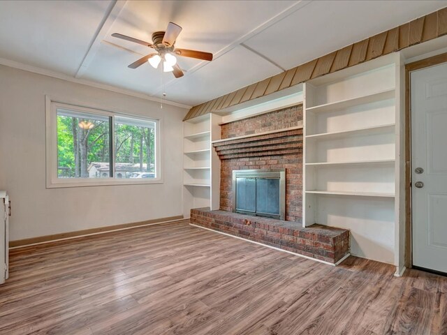 1313 Glass Ave, Diboll, TX 75941 - unfurnished living room with wood finished floors, a brick fireplace, ceiling fan, built in shelves, and crown molding