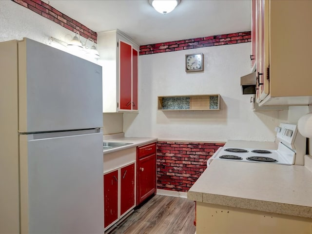 1313 Glass Ave, Diboll, TX 75941 - kitchen with white appliances, light wood finished floors, light countertops, red cabinetry, and brick wall