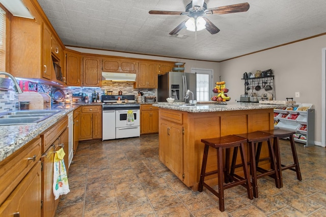 kitchen with sink, backsplash, an island with sink, white appliances, and a kitchen bar