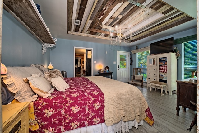 bedroom featuring hardwood / wood-style floors, a notable chandelier, and a raised ceiling