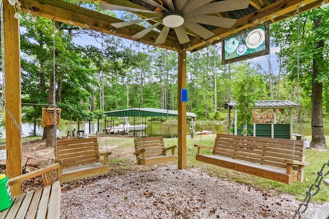 view of yard featuring a dock, ceiling fan, and a water view