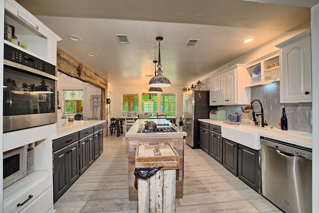 kitchen with stainless steel appliances, white cabinetry, a kitchen island, and light wood-type flooring