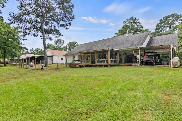 rear view of property with a carport, a sunroom, and a yard