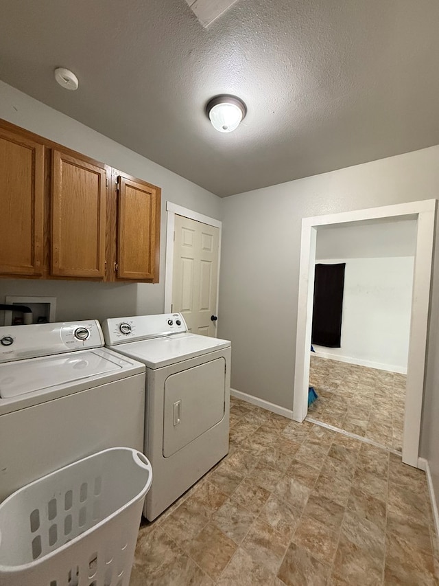 laundry room with independent washer and dryer, cabinets, and a textured ceiling