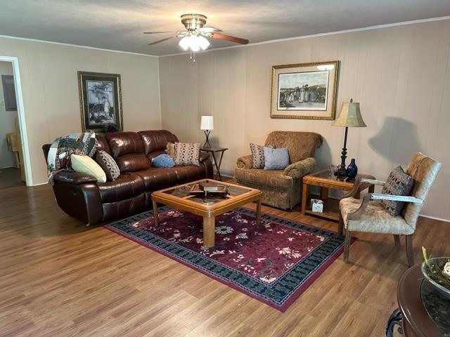 living room with ceiling fan, wood-type flooring, and ornamental molding