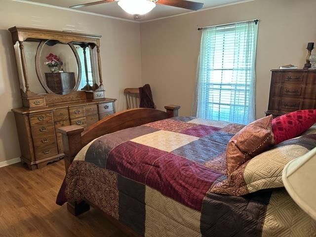 bedroom featuring ceiling fan, hardwood / wood-style floors, and ornamental molding