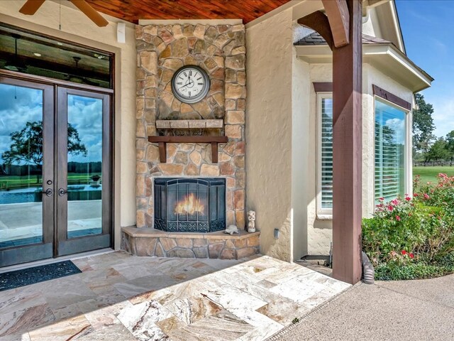 view of patio / terrace with ceiling fan, a water view, pool water feature, and an outdoor stone fireplace