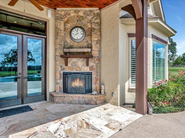 exterior space featuring an outdoor stone fireplace, ceiling fan, wooden ceiling, and french doors