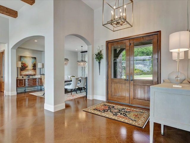 1811 Caspers Cv, Lufkin, TX 75904 - tiled foyer featuring a high ceiling, arched walkways, a chandelier, french doors, and beam ceiling
