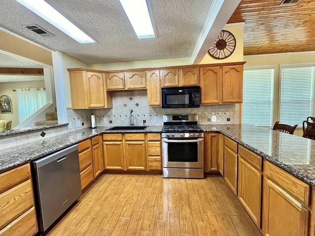 670 Cedar Crest Cir, Hemphill, TX 75948 - kitchen featuring stainless steel appliances, a sink, a peninsula, light wood finished floors, and dark stone counters