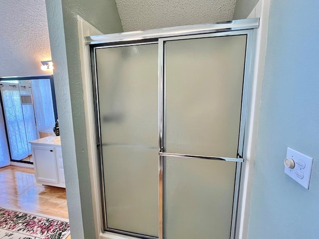 670 Cedar Crest Cir, Hemphill, TX 75948 - bathroom with a textured wall, a stall shower, vanity, and wood finished floors