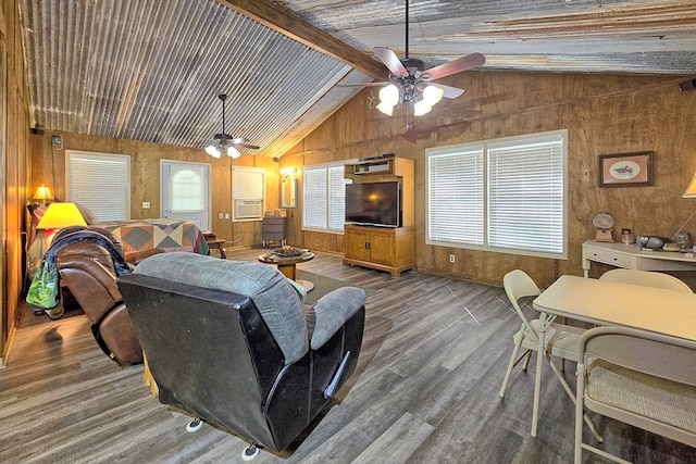 living room featuring vaulted ceiling with beams, dark hardwood / wood-style flooring, ceiling fan, and wooden walls