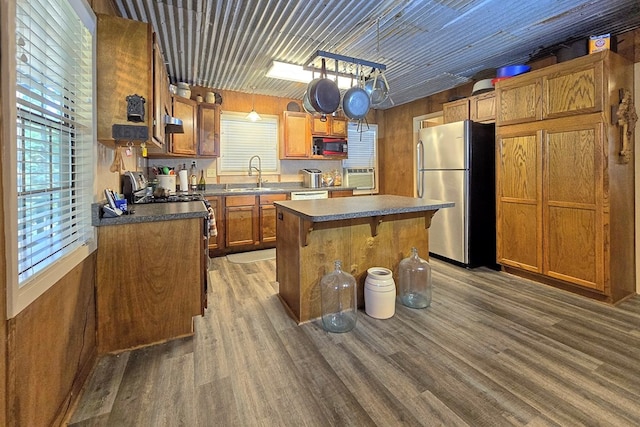 kitchen featuring a center island, dark wood-type flooring, a kitchen breakfast bar, hanging light fixtures, and stainless steel refrigerator