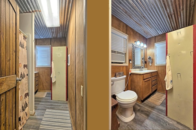 bathroom featuring wooden walls, hardwood / wood-style floors, vanity, and toilet