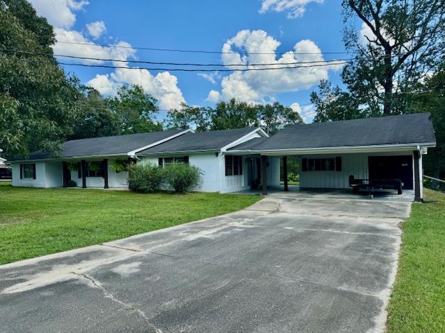 ranch-style home featuring a front lawn and a carport