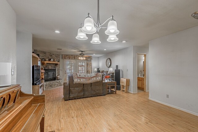 1500 New Haven Rd, Hemphill, TX 75948 - living room with a stone fireplace, light hardwood / wood-style flooring, and ceiling fan with notable chandelier