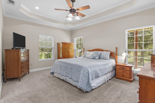 bedroom featuring crown molding, ceiling fan, a tray ceiling, and light carpet