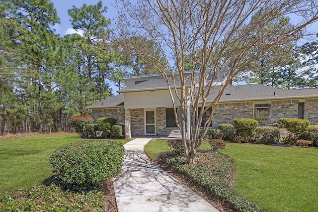 view of front facade with a shingled roof, brick siding, and a front lawn