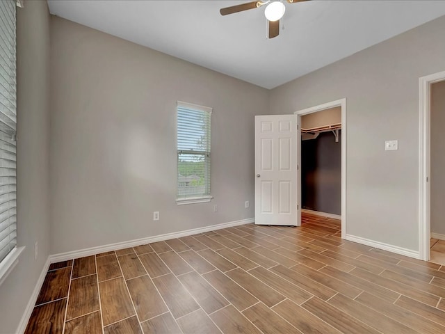 unfurnished bedroom featuring a spacious closet, ceiling fan, light wood-type flooring, and a closet