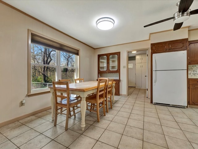 tiled dining room with ceiling fan and ornamental molding