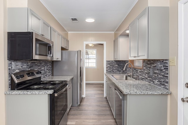 kitchen featuring sink, crown molding, light hardwood / wood-style flooring, appliances with stainless steel finishes, and decorative backsplash