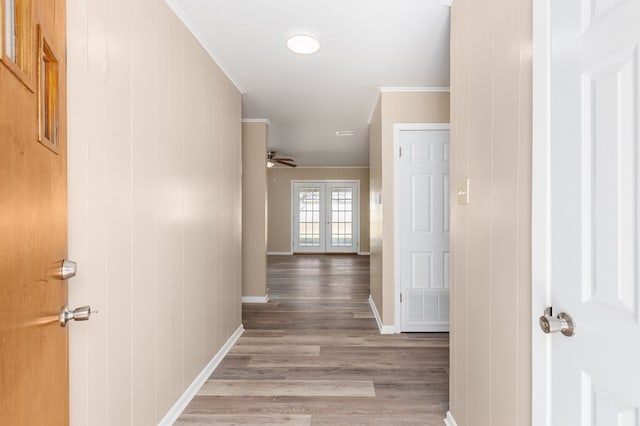 hall with hardwood / wood-style flooring, ornamental molding, and french doors