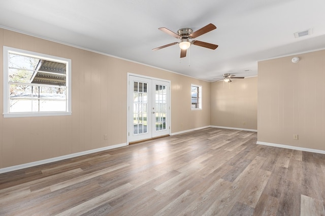 empty room featuring ornamental molding, a wealth of natural light, light hardwood / wood-style floors, and french doors