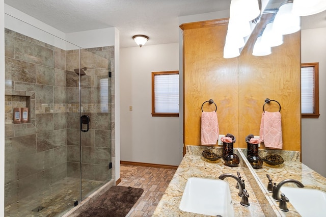 bathroom with a textured ceiling, vanity, and a shower with shower door