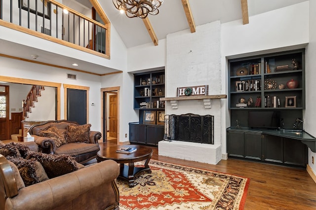 living room featuring a towering ceiling, a fireplace, built in shelves, beamed ceiling, and dark hardwood / wood-style floors