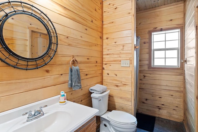 bathroom with wooden walls, vanity, and toilet