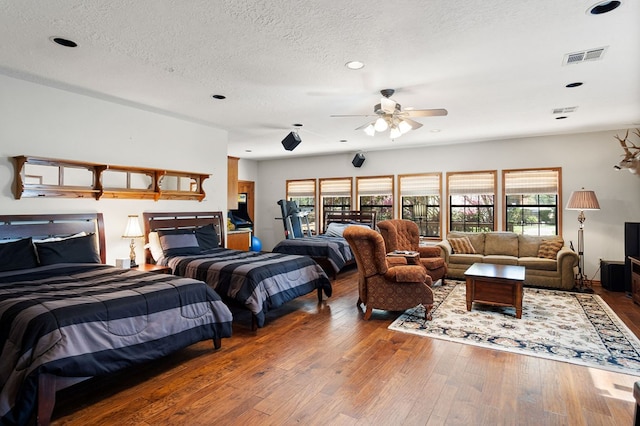 bedroom with ceiling fan, wood-type flooring, and a textured ceiling