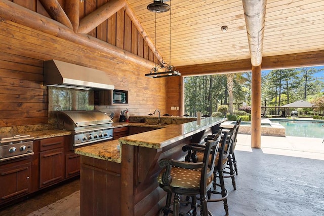 view of patio with area for grilling, exterior kitchen, and an outdoor wet bar