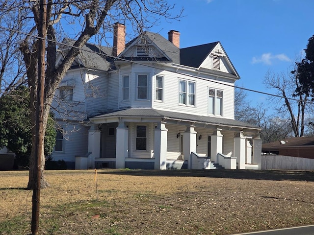 victorian house featuring a chimney and a front yard