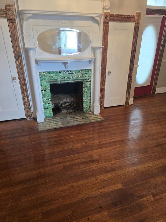 unfurnished living room with a tiled fireplace and wood finished floors