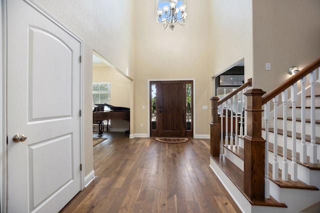 entryway featuring stairway, a wealth of natural light, hardwood / wood-style flooring, and an inviting chandelier
