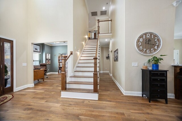 foyer featuring stairway, baseboards, wood finished floors, and a towering ceiling