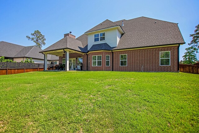 rear view of house featuring a fenced backyard, roof with shingles, a chimney, and a lawn