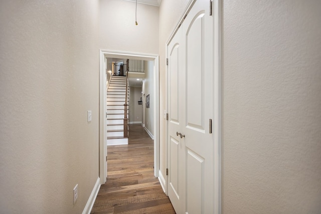 corridor featuring attic access, baseboards, dark wood-style flooring, and a textured wall
