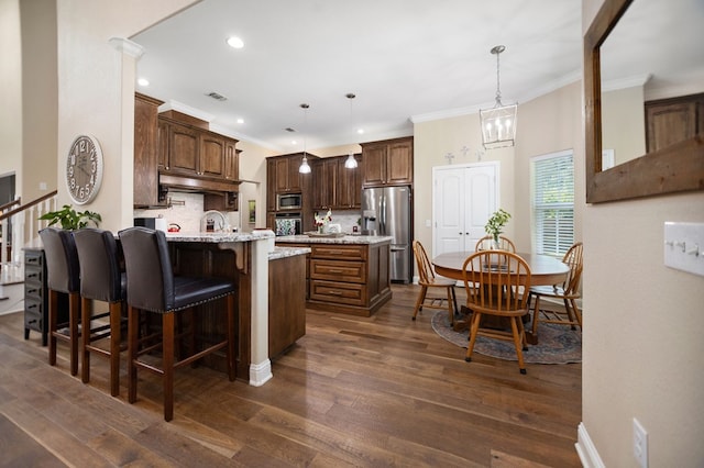 kitchen featuring crown molding, a kitchen breakfast bar, stainless steel appliances, backsplash, and a peninsula