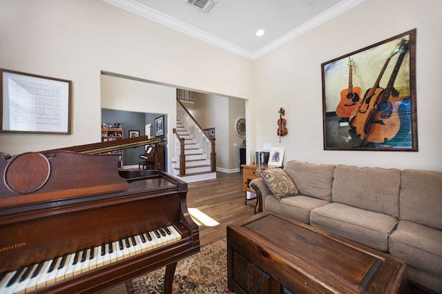 living room with wood finished floors, visible vents, ornamental molding, baseboards, and stairs