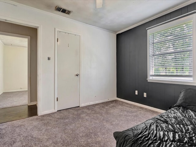 carpeted bedroom featuring crown molding, a ceiling fan, visible vents, and baseboards