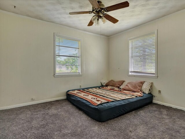 carpeted bedroom with ornamental molding, ceiling fan, and baseboards