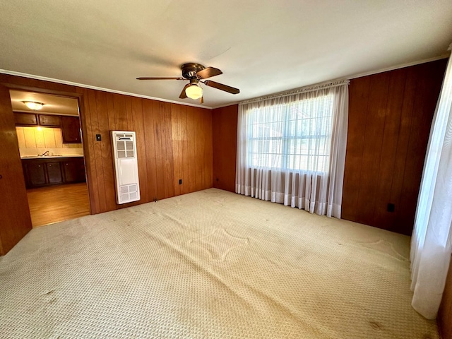 unfurnished bedroom with ceiling fan, ensuite bathroom, light colored carpet, and wood walls