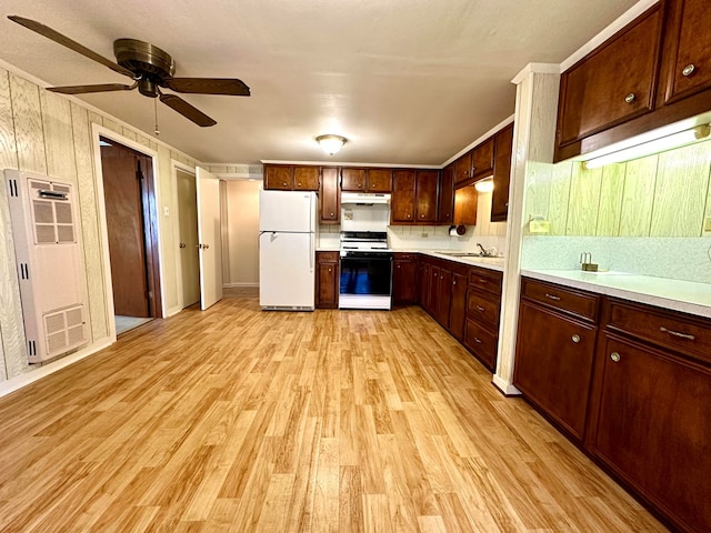 kitchen featuring white appliances, sink, wooden walls, ceiling fan, and light wood-type flooring