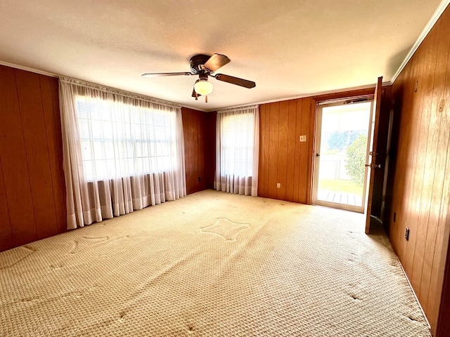 carpeted spare room with ceiling fan and wooden walls