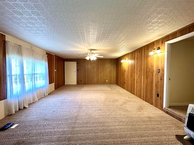 carpeted spare room featuring ceiling fan, wood walls, and heating unit