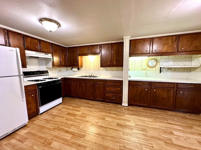 kitchen with light wood-type flooring, backsplash, dark brown cabinets, white appliances, and sink